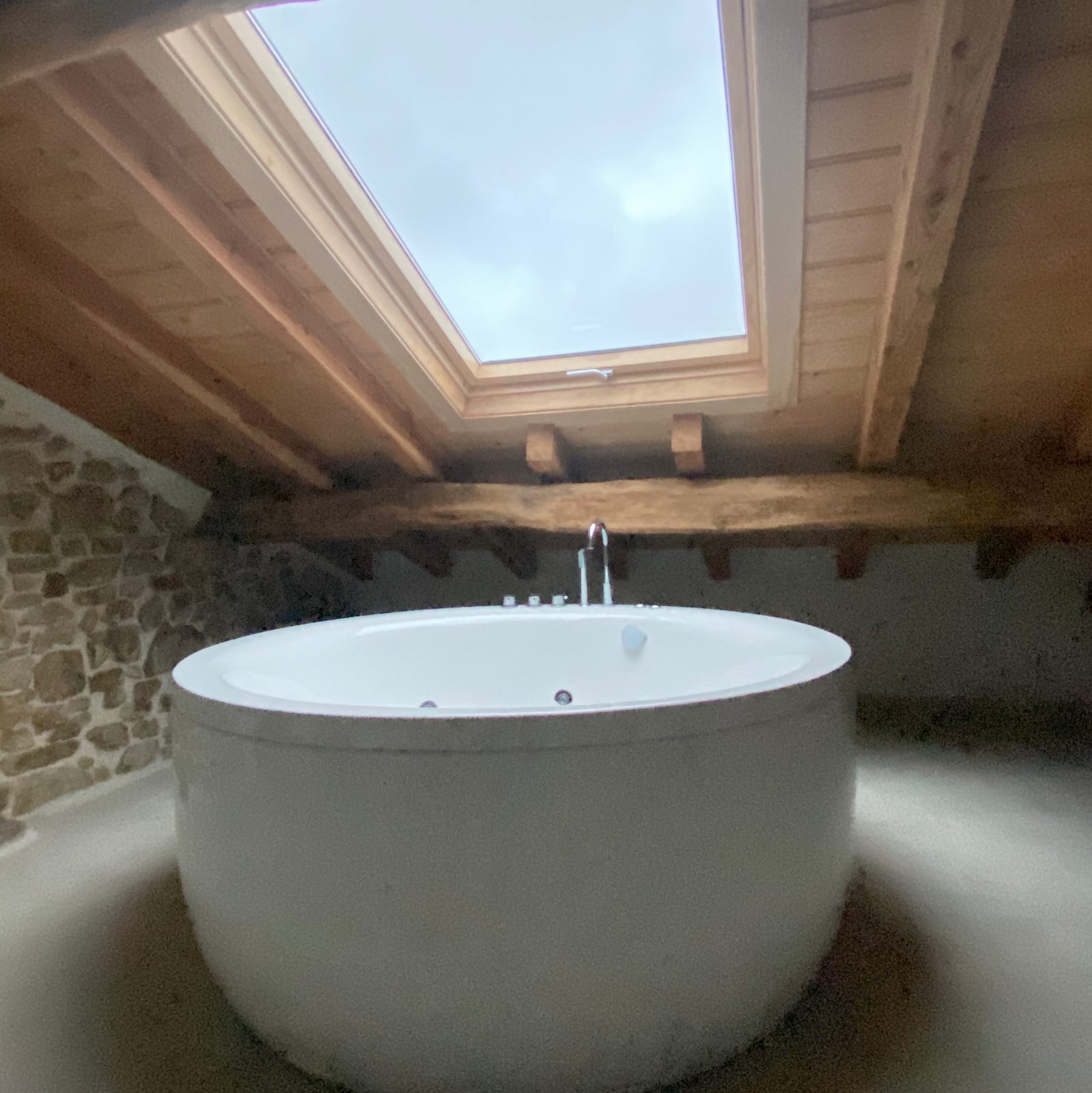 Bañera circular de hidromasaje bajo la ventana del tejado